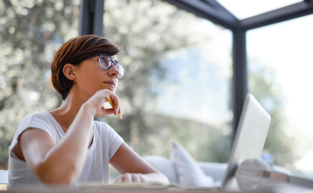 A lady sitting at her laptop pausing for thought wishing that her software would work more like she does