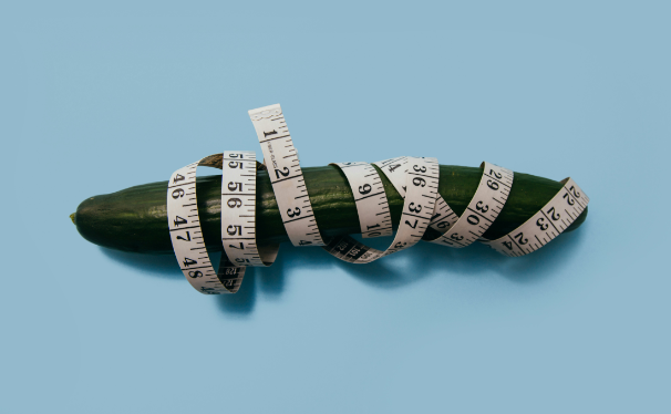 A cucumber with a measuring tape wrapped around it.